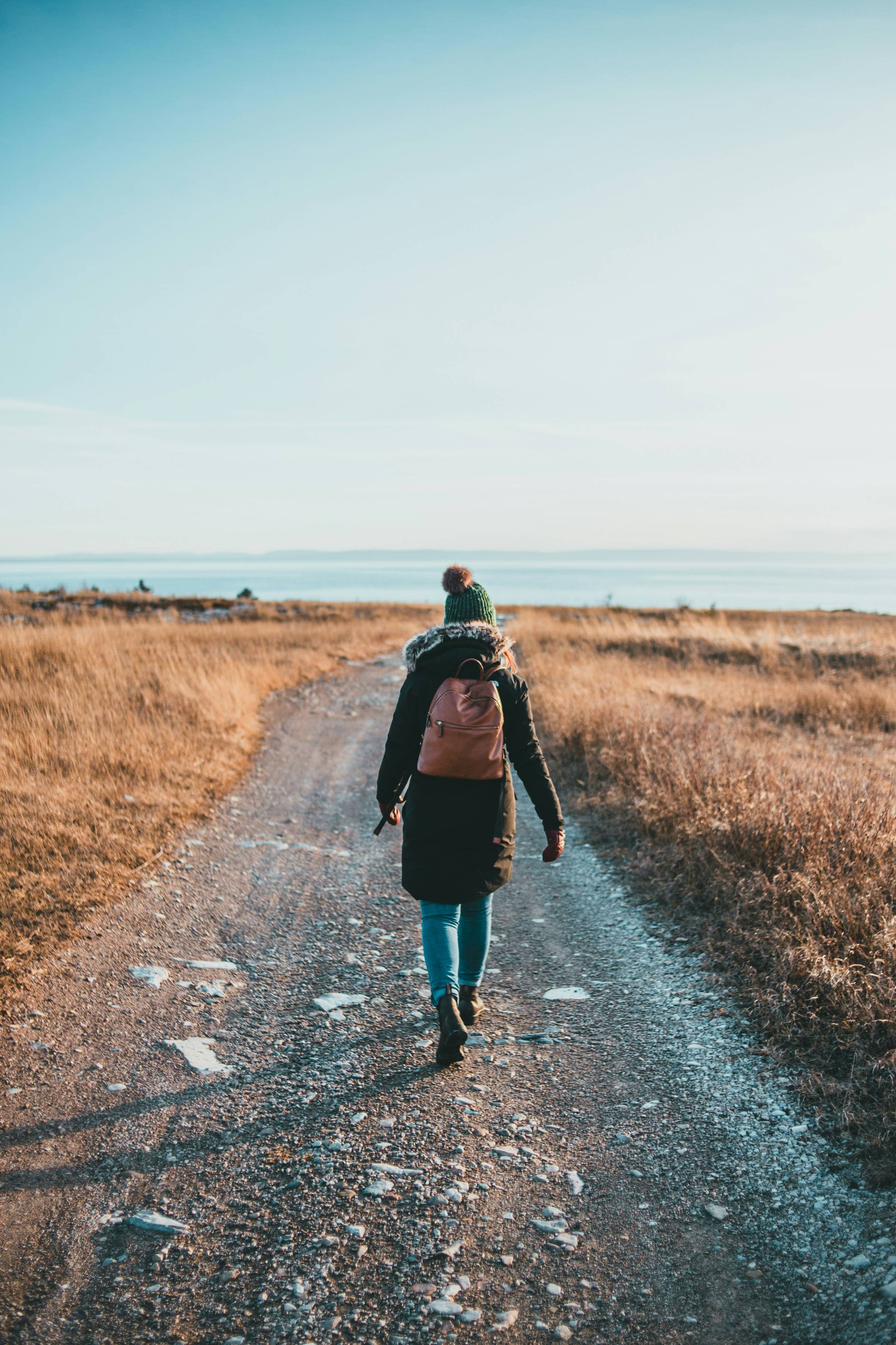 woman walking on a rocky trail through a field