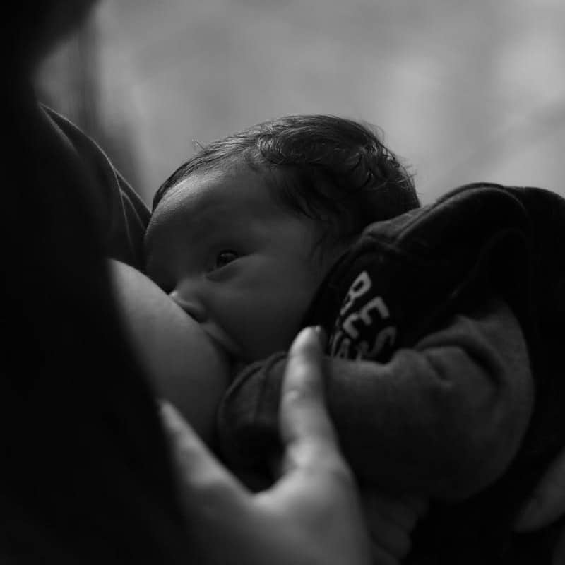 woman in black hoodie carrying baby in blue onesie