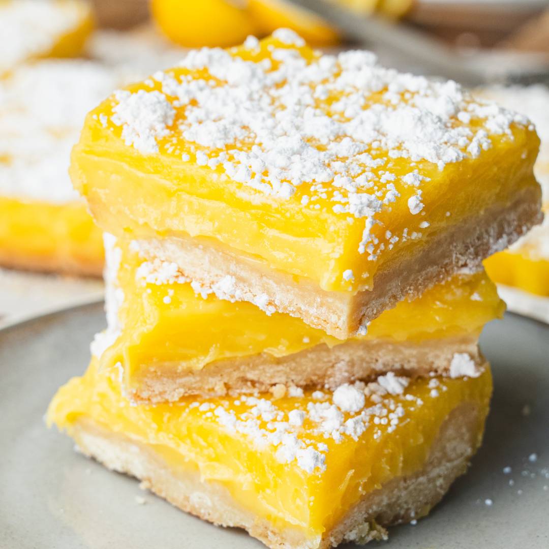 fresh lemon bars are stacked on a plate