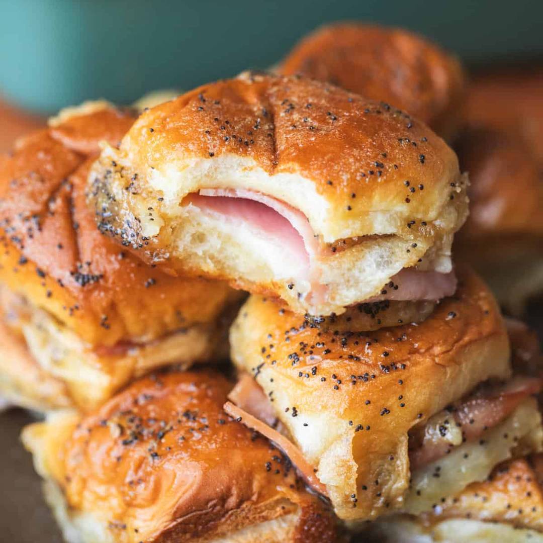 ham and cheese sliders sit stacked on a plate