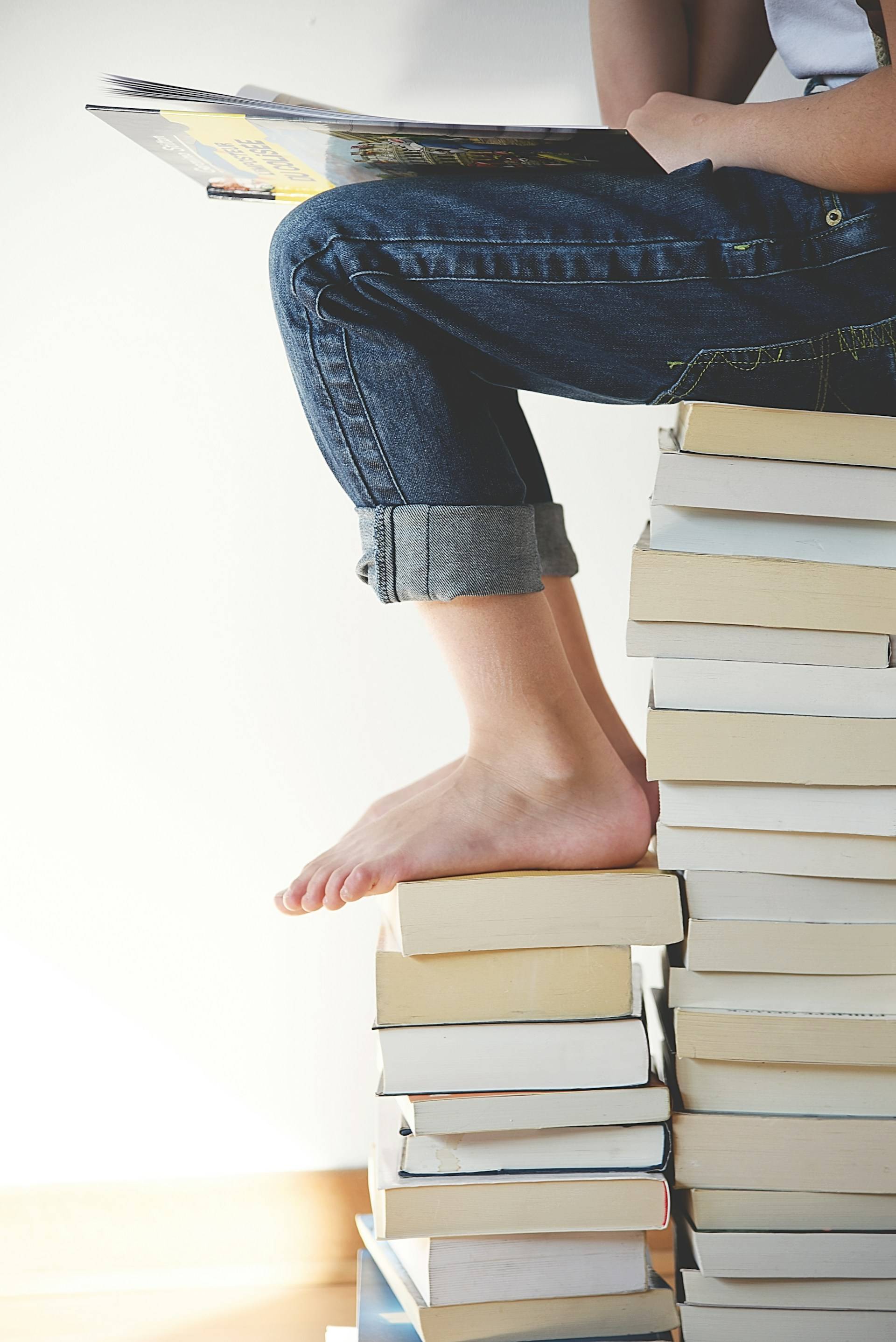 A woman sitting on a stack of books, her unbegun things.