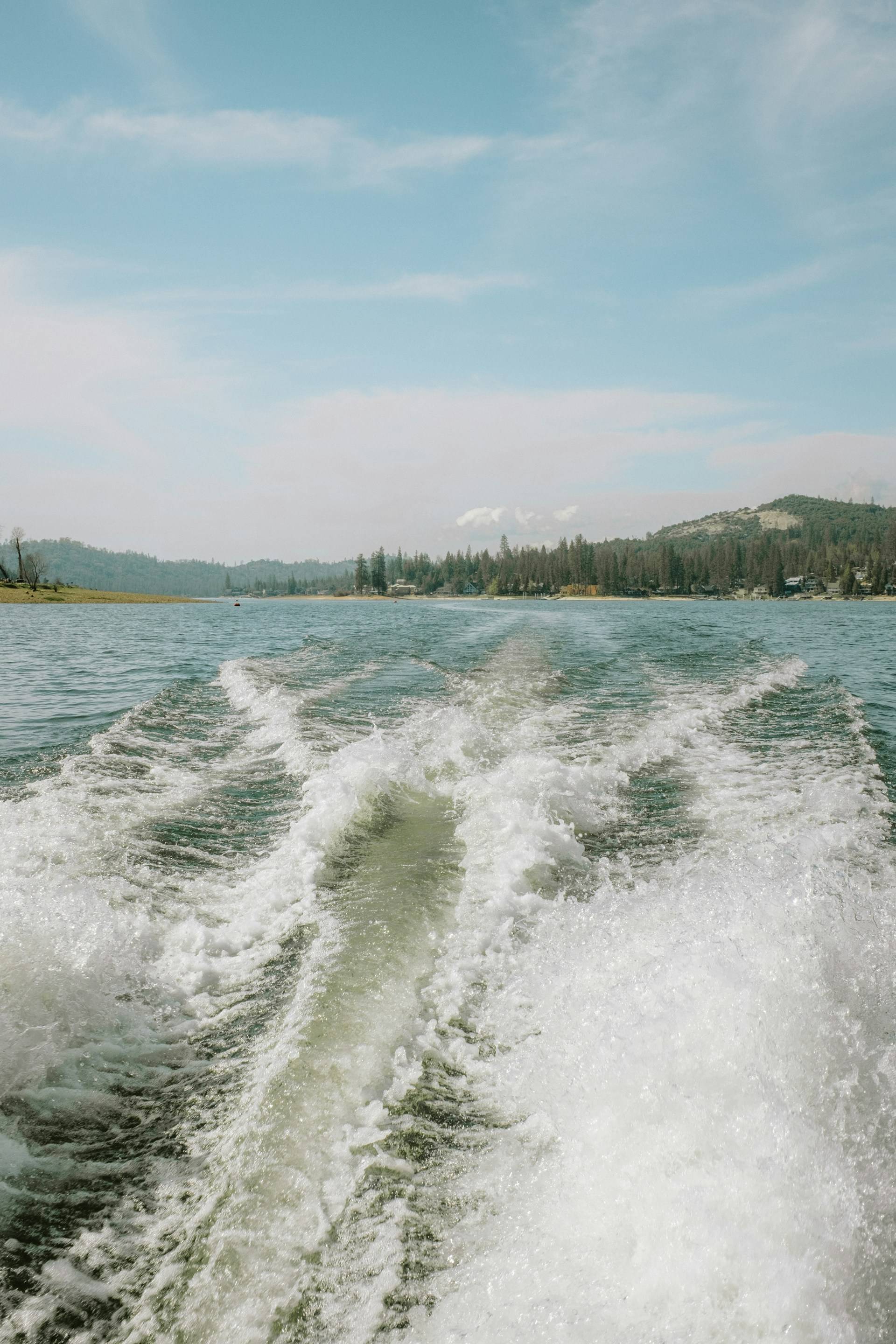 The wake behind a power boat with beautiful landscape in the background.