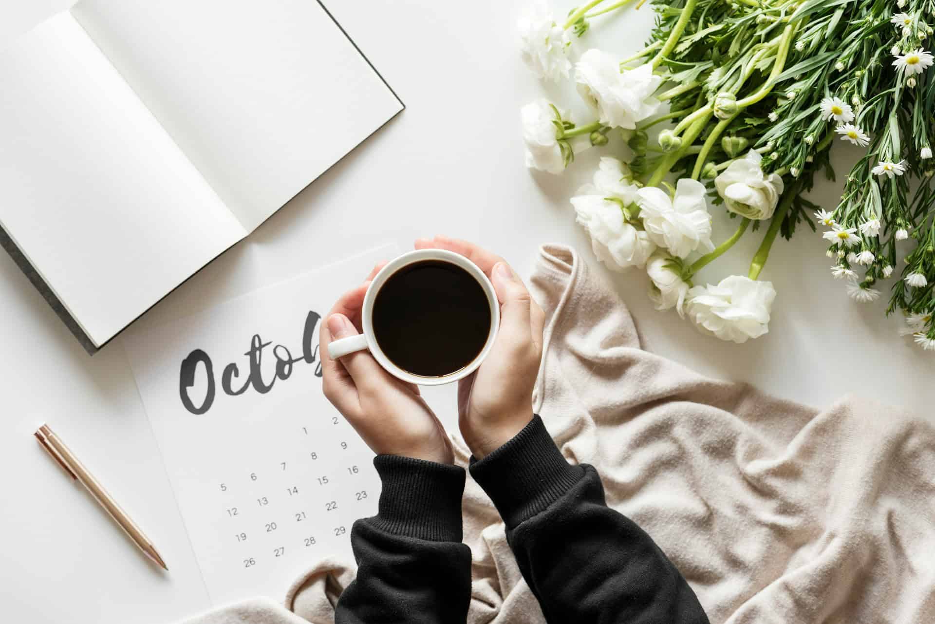 A woman's hands cupping a coffee as she tackles 5 things to do in October.
