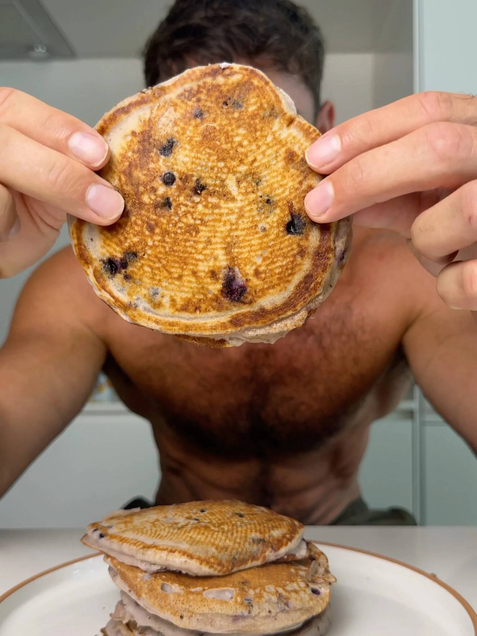 A forkful of blueberry pancakes above a syrupy stack