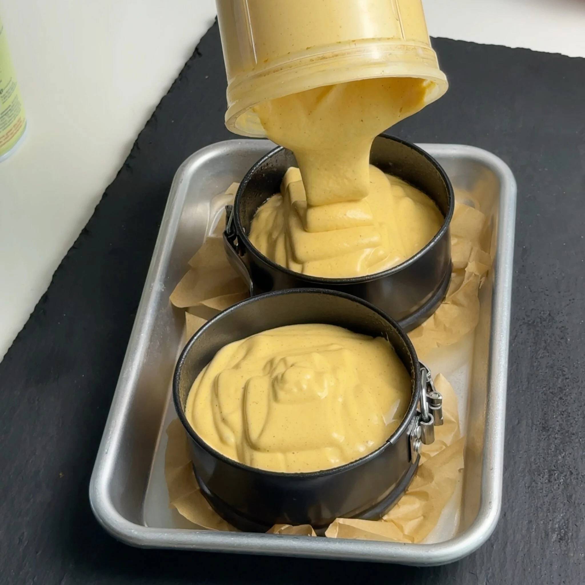 Pumpkin cheesecake batter being poured into two mini springform pans