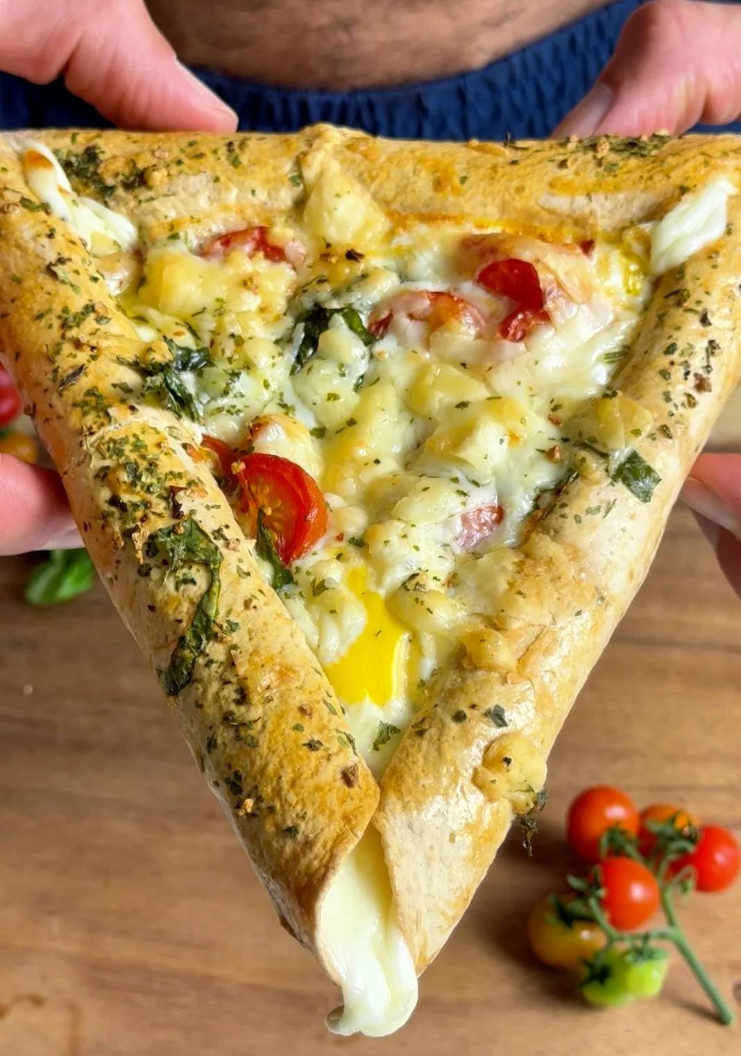 A triangular stuffed-crust Italian omelet on a wooden board