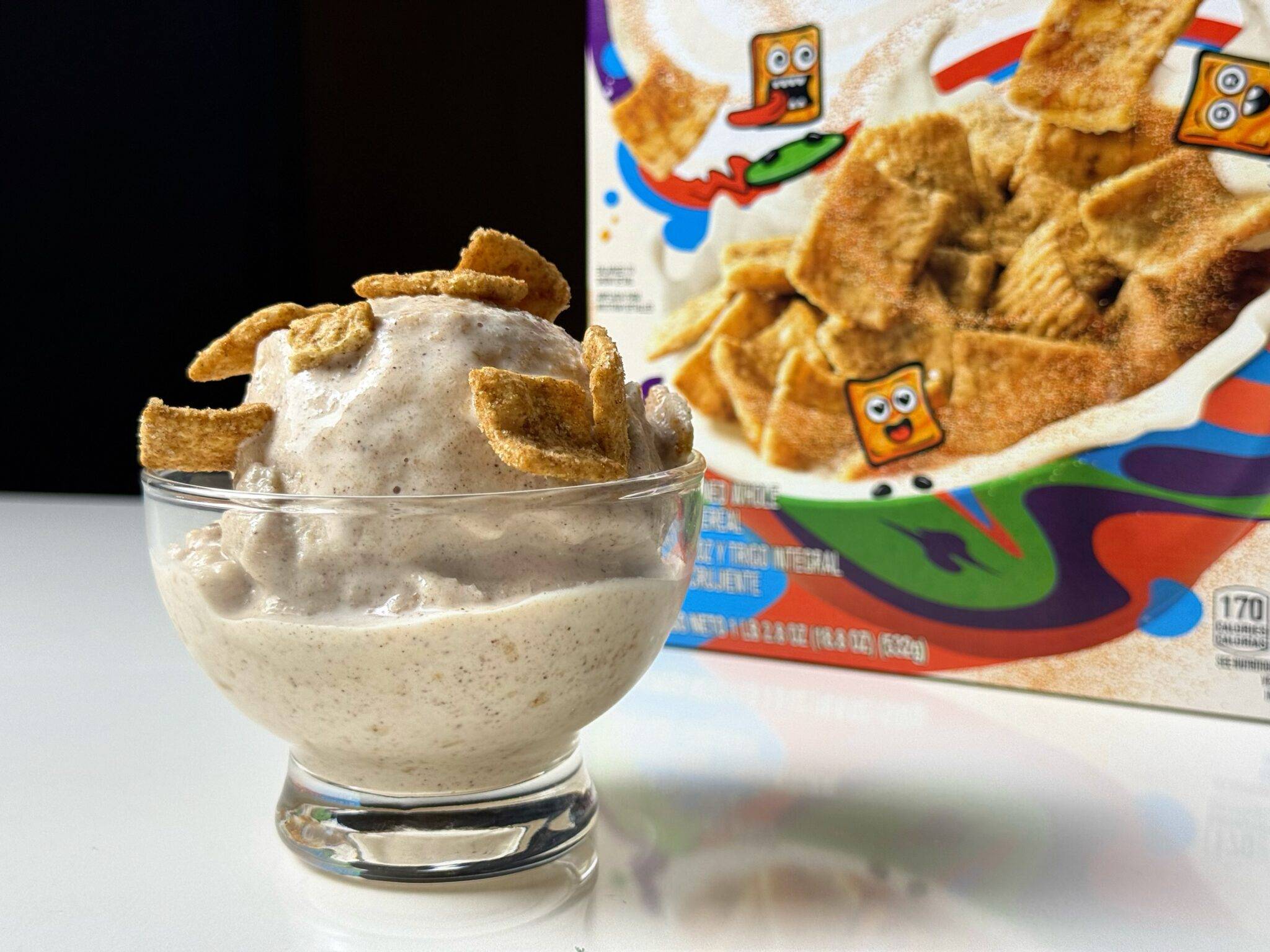 Cinnamon Toast Crunch Creami in a glass bowl beside the cereal box