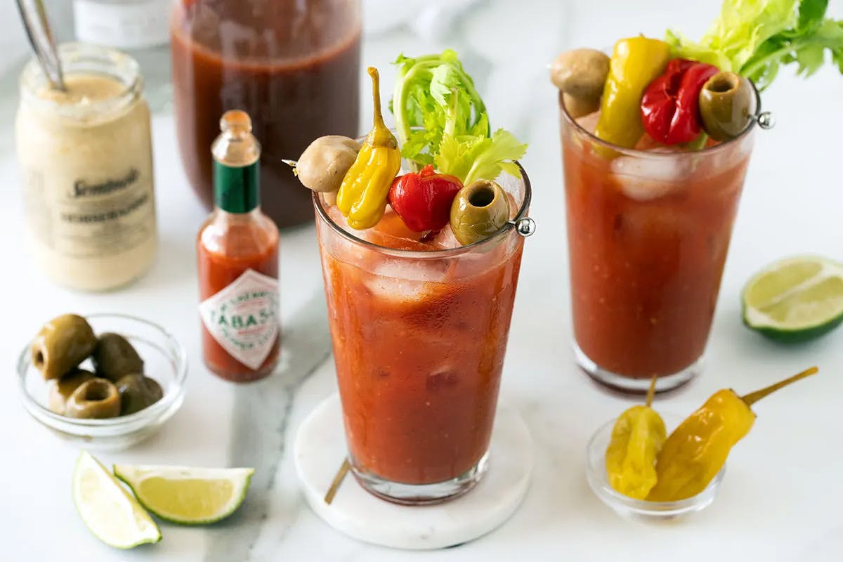 Ultimate Bloody Caesar on a table with tabasco sauce loaded with garnishments 