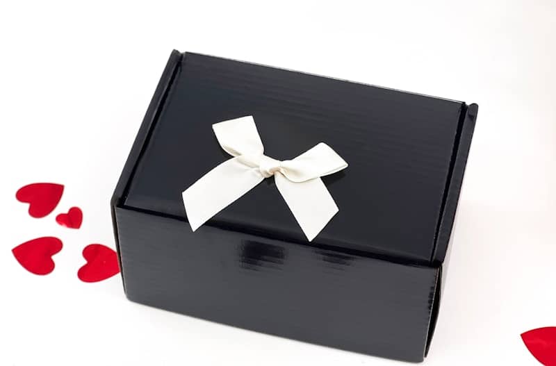 A black gift box with a white ribbon and hearts.