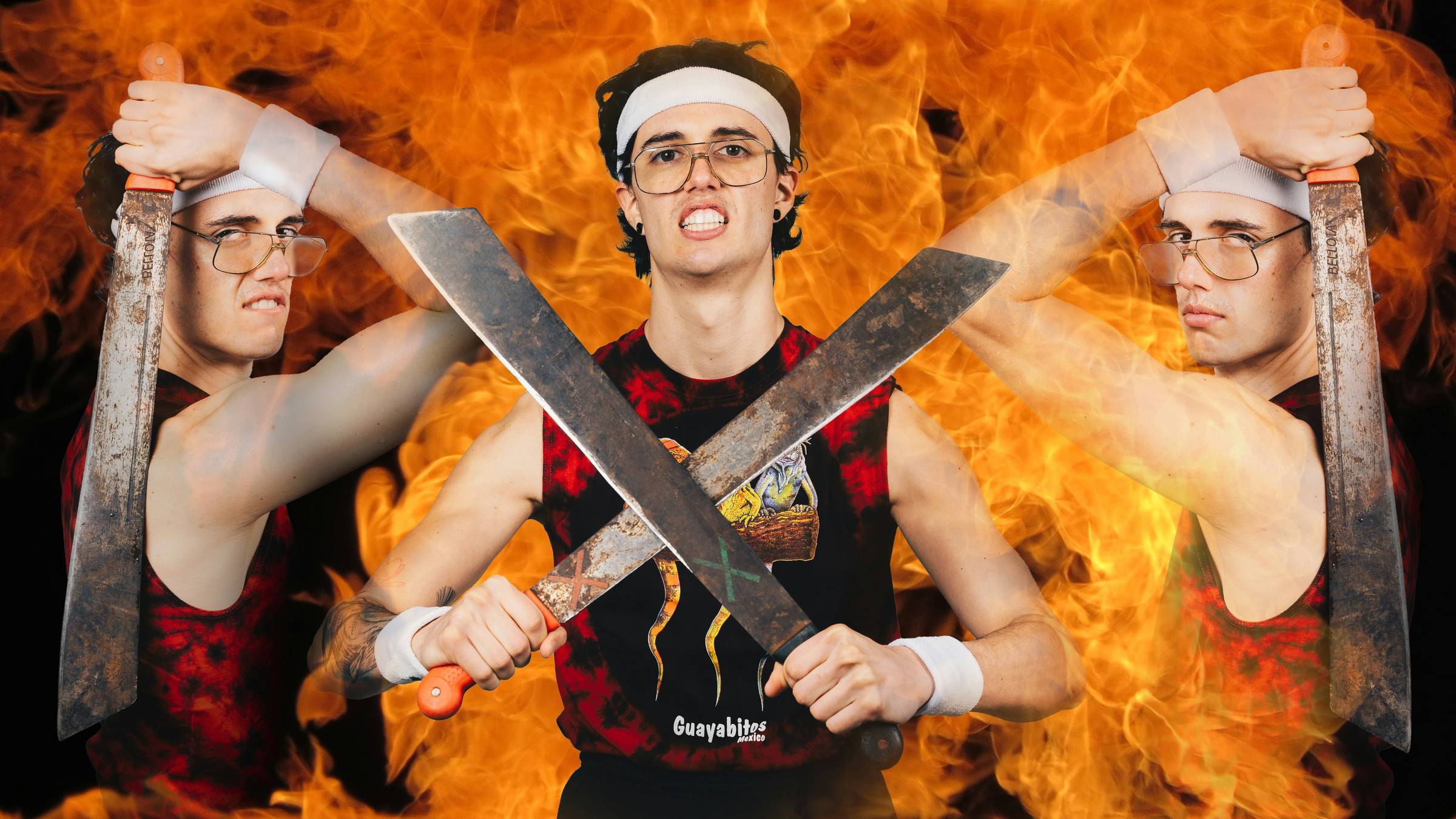 nerdy white guy with a headband brandishing two machetes in front of a backdrop of fire