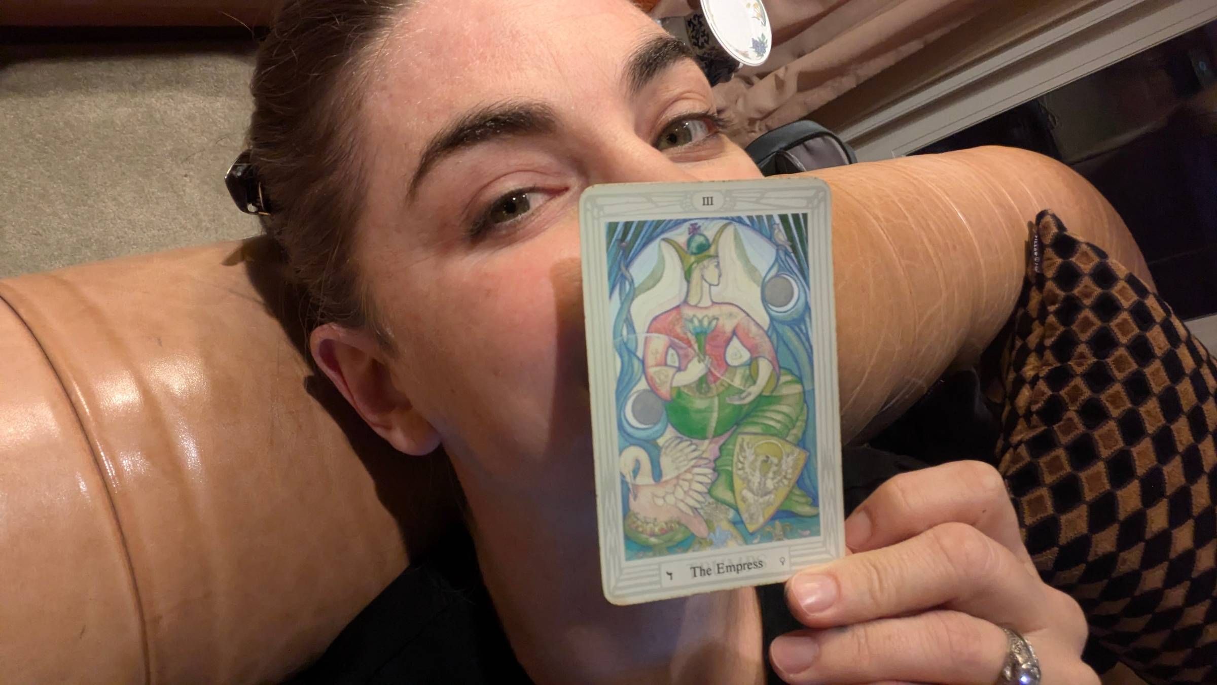 photo of a white woman (Rachel) holding the Empress tarot card in front of her mouth