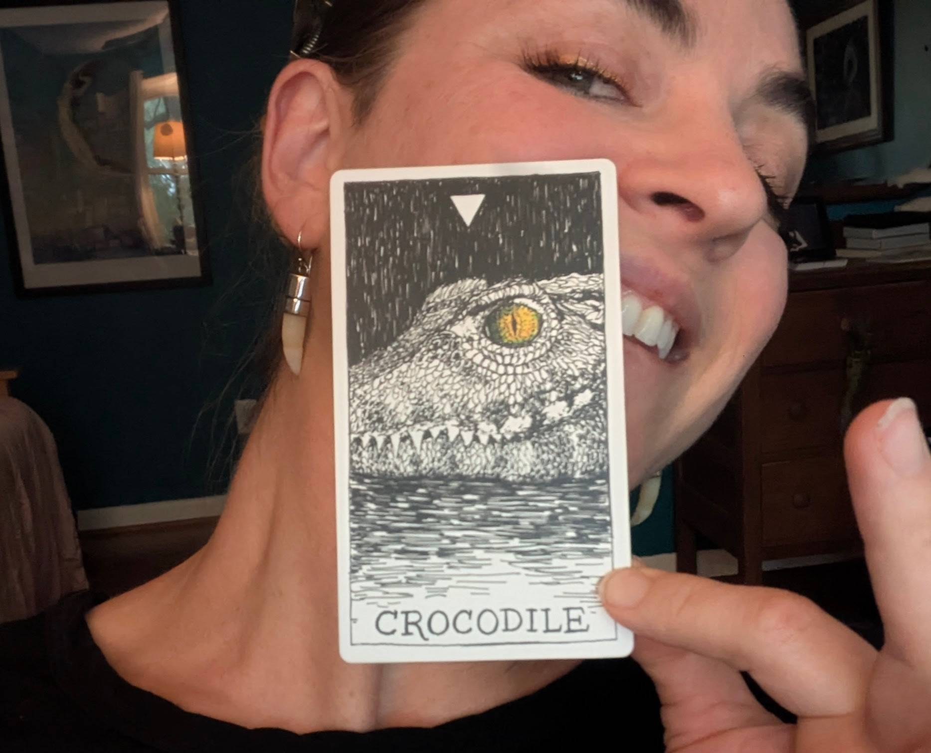 Rachel holds a crocodile animal spirit card up in front of her face
