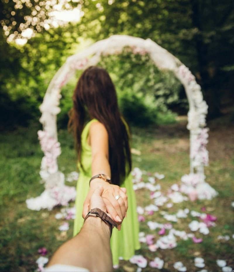 man and woman holding hands near flower