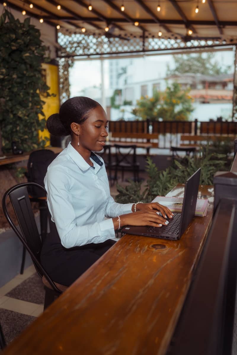 A woman working on a laptop at an outdoor cafe.