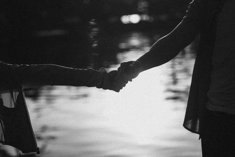Two people holding hands by the water