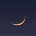 A view of a mountain with a half moon in the sky