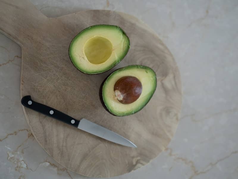 An avocado cut in half with a knife.