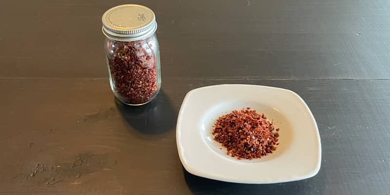Homemade paprika powder in a white dish and a small spice jar.