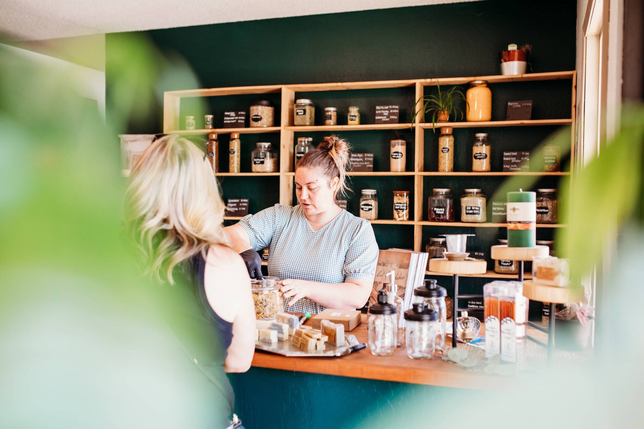 Serra measuring out bulk herbs at Vine & Branch Shop in Paradise, CA