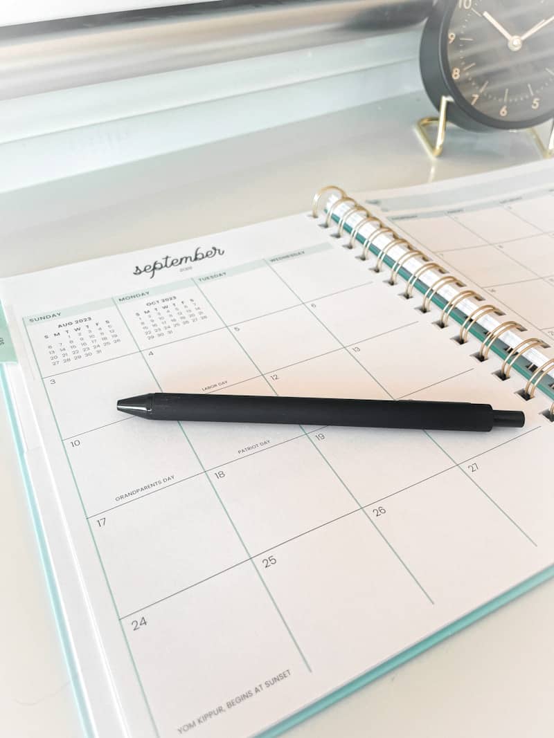 A black pen rests on an open september calendar.
