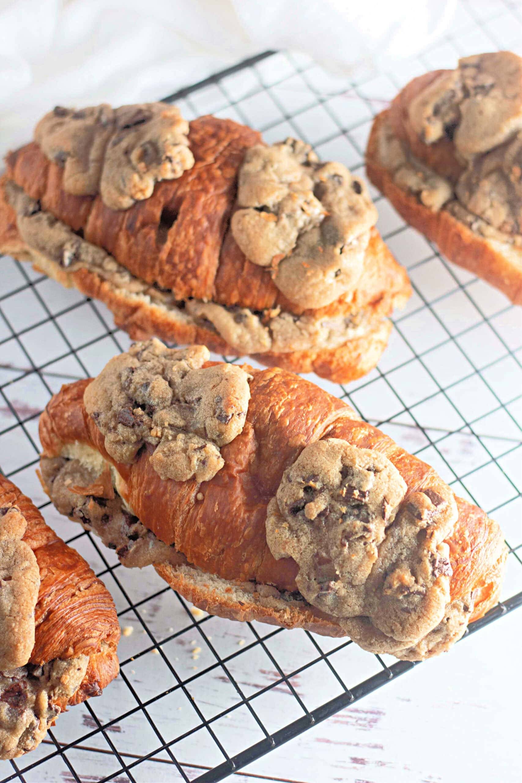 a wire cooling rack has chocolate chip cookie croissants cooling on it