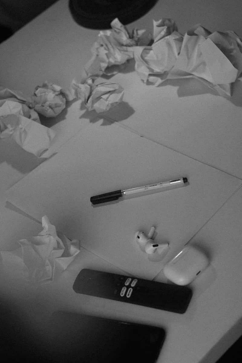 A white table topped with a cell phone and a pile of crumpled paper