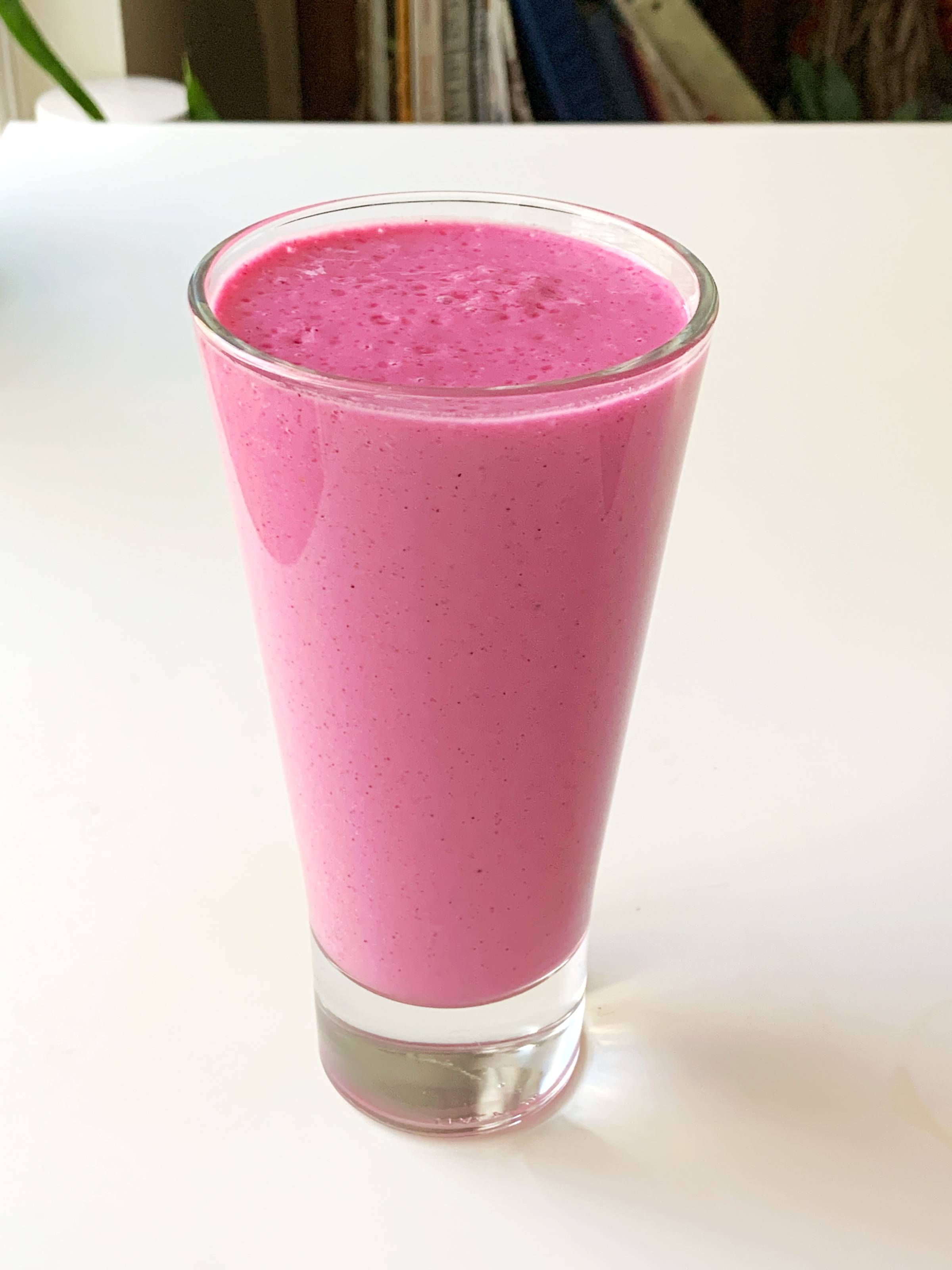 Pink dragonfruit raspberry smoothie made in a tall glass