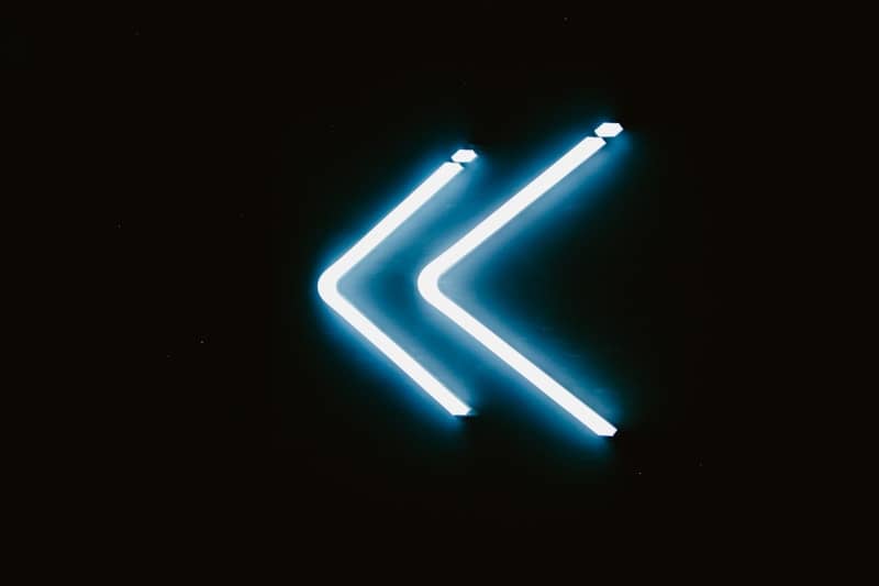 Blue neon chevron symbol on black background
