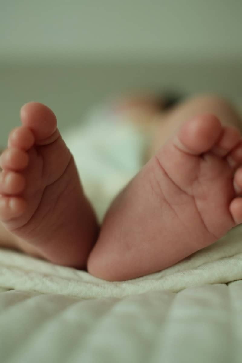 The small feet of a baby resting on a soft white blanket