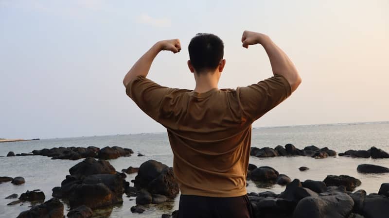 Man flexing muscles on a rocky shore