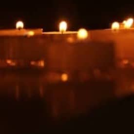 Lit candles illuminate a dark room.