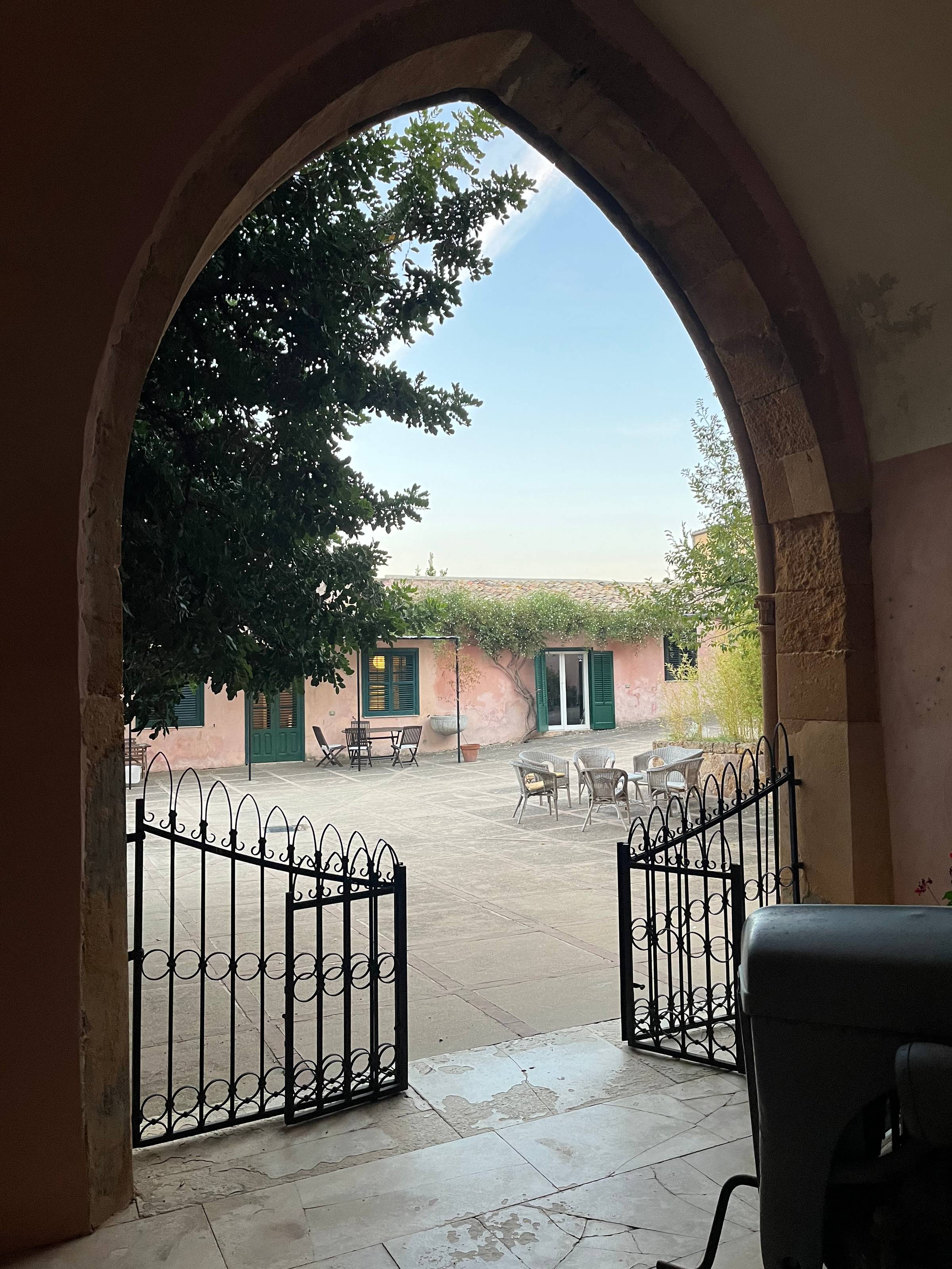 An agriturismo farm with old pink buildings and a stone archway