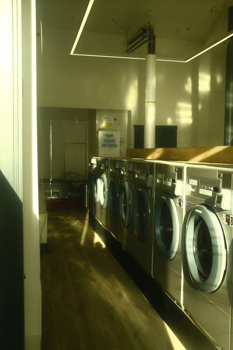 A laundry room with many shiny washing machines.