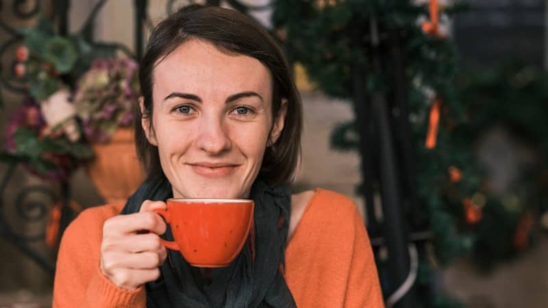 a woman holding a cup of coffee in front of her face