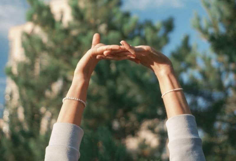 a person reaching up into the air to catch a frisbee