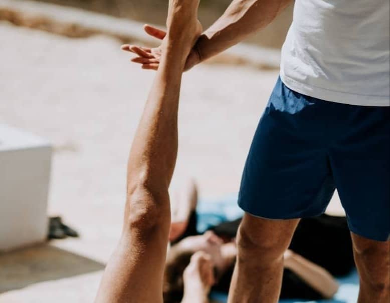 man lying on floor near man standing holding his leg