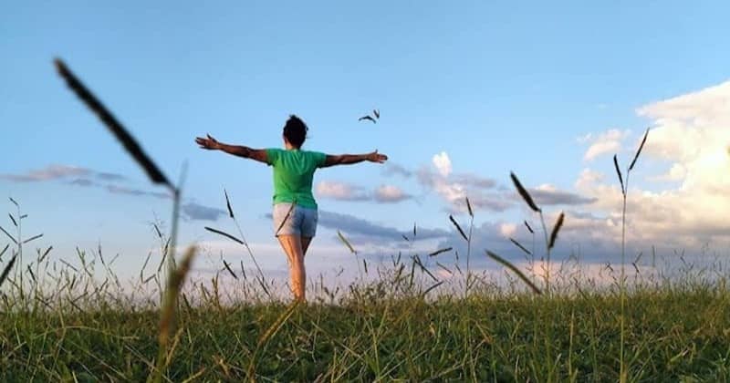 A woman standing in a field with her arms outstretched