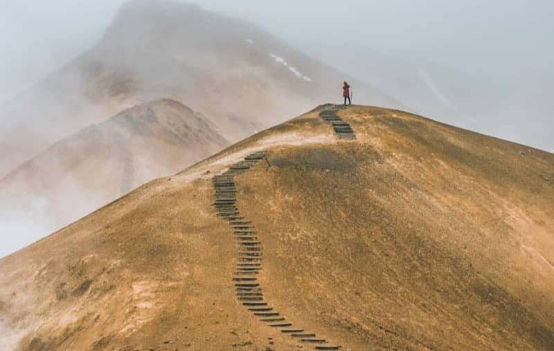 man on top brown hill