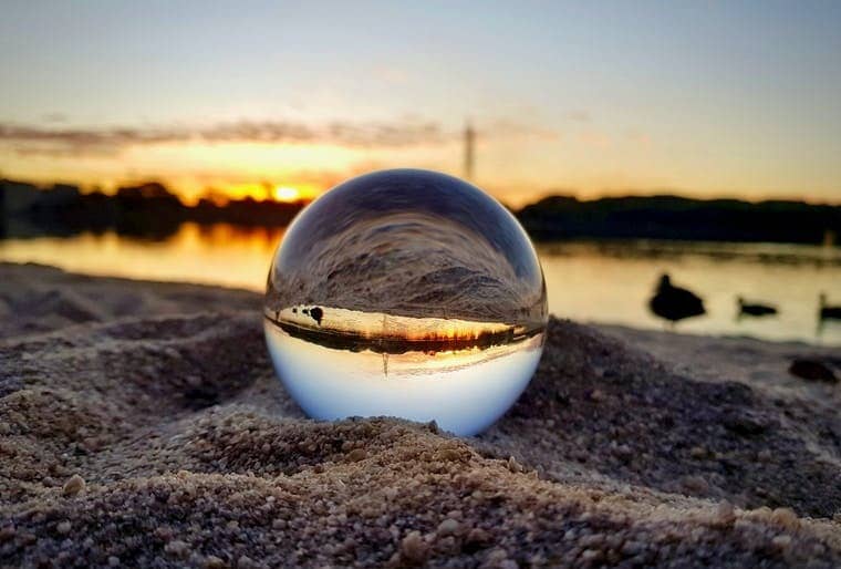 clear glass ball on brown sand during sunset