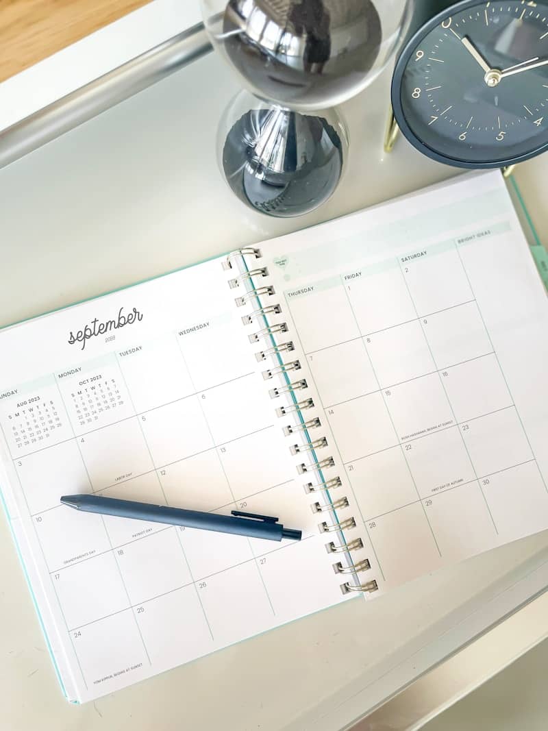 An open september planner with a pen, hourglass, and clock