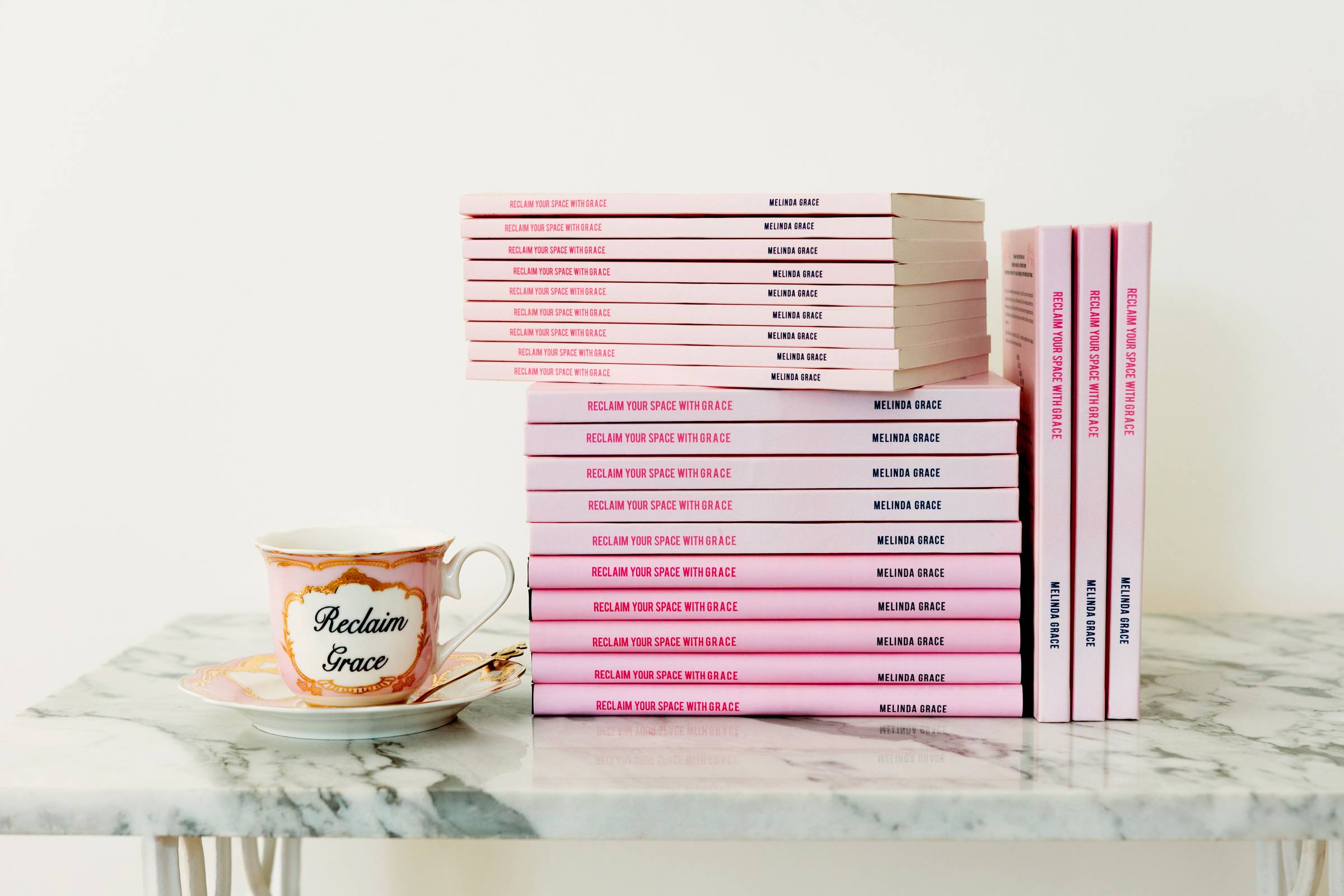 Pink Books on a marble table with a tea cup.