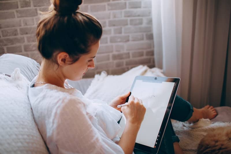 woman in white shirt holding white tablet computer