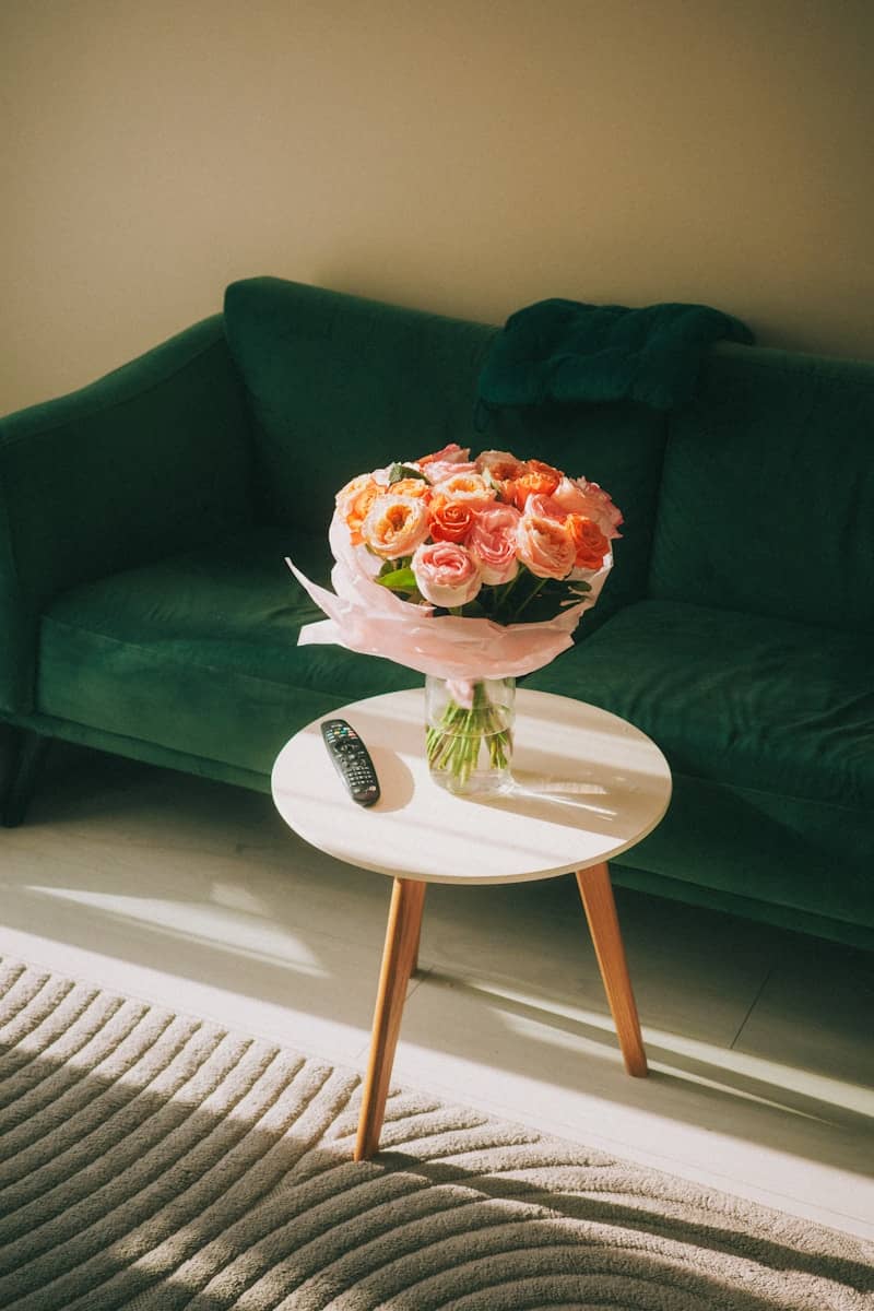 A vase of colorful roses sits on a small table.