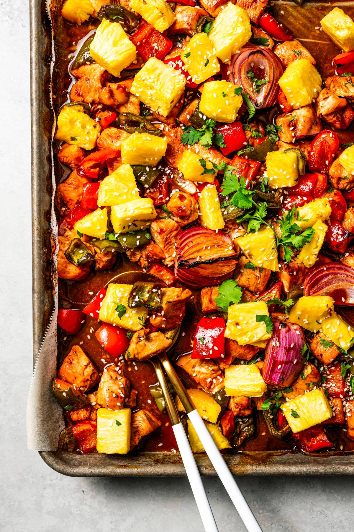 chopped chicken, pineapples, and vegetables on a sheet pan to make Hawaiian chicken.