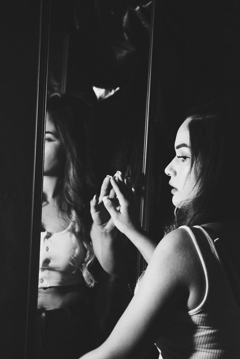 Black and white photo of woman touching her reflection in mirrorr
