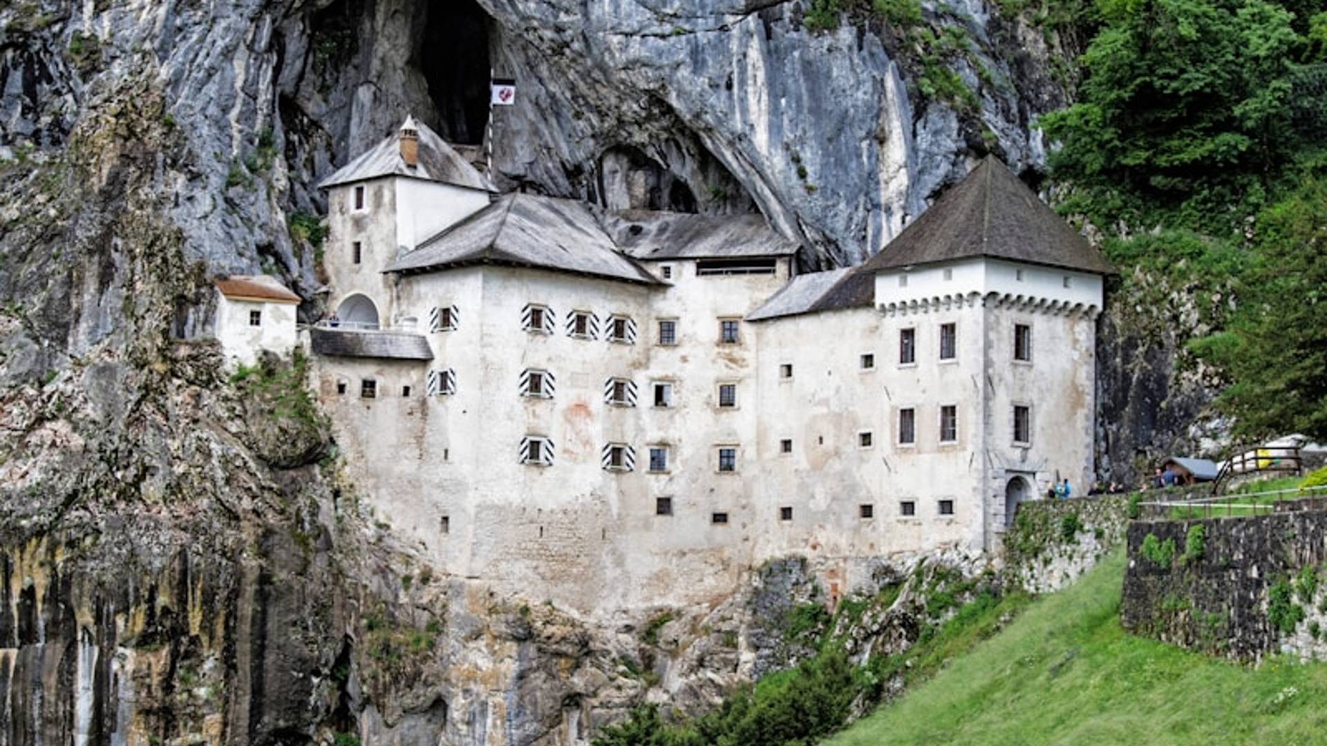 white concrete building near green grass field and trees during daytime