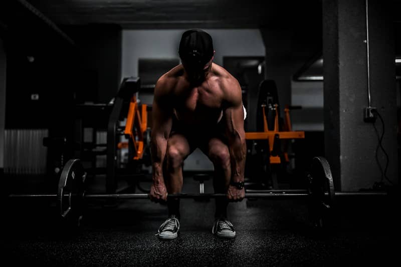 Muscular person lifting barbell in gym