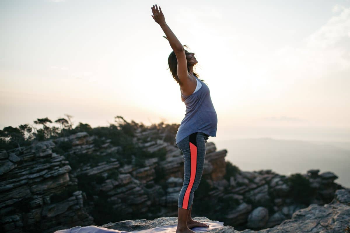 Pregnant Woman Saluting to the Sun Yoga on Mountain at Sunrise