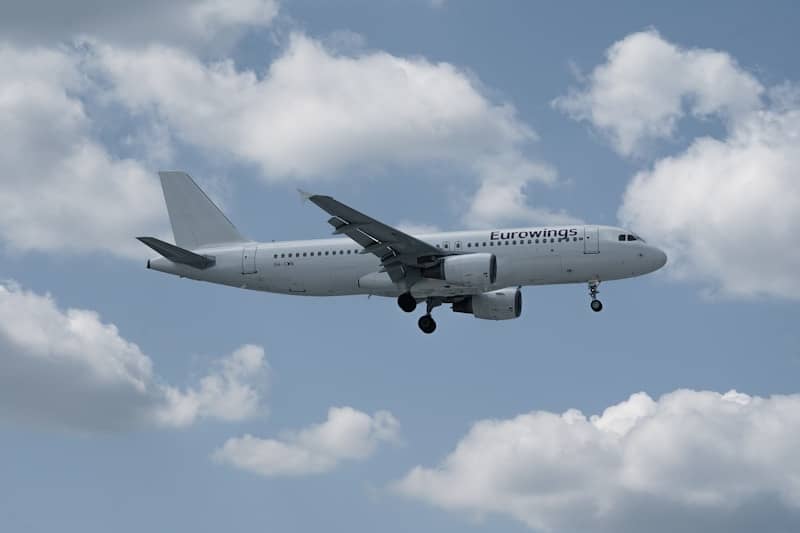 White airplane flying in a cloudy blue sky