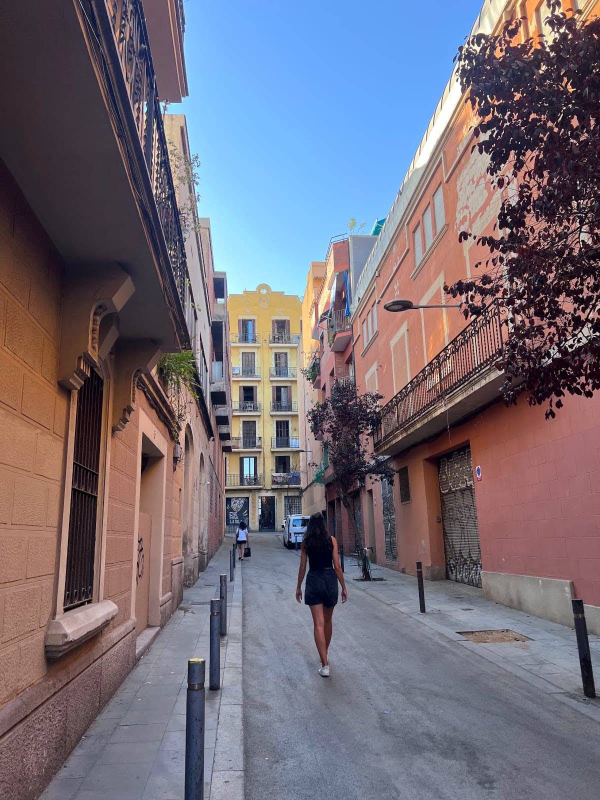 Katharina walking down a narrow street surrounded by colorful buildings in Barcelona.